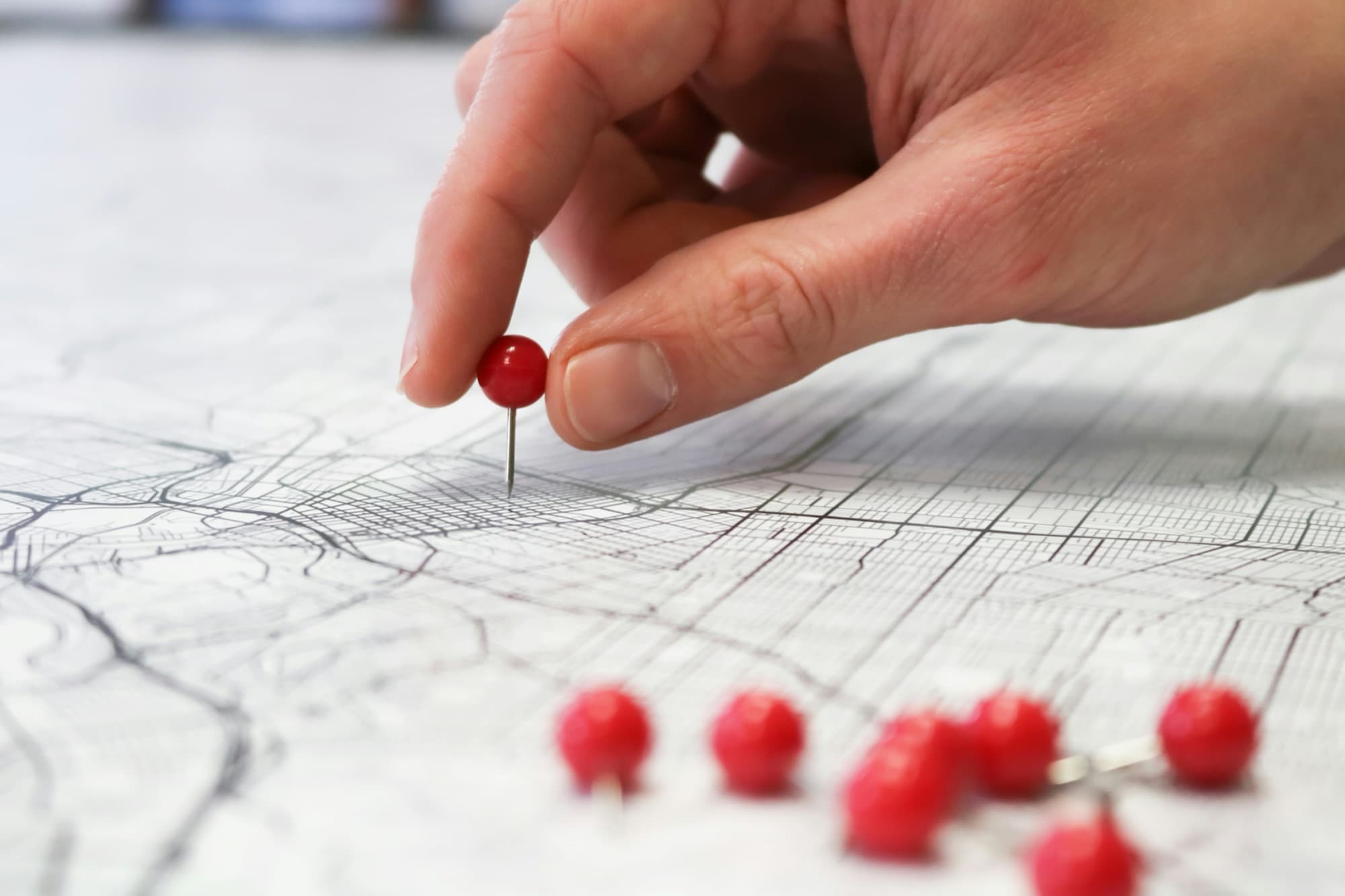 Hand placing a pin on a city map